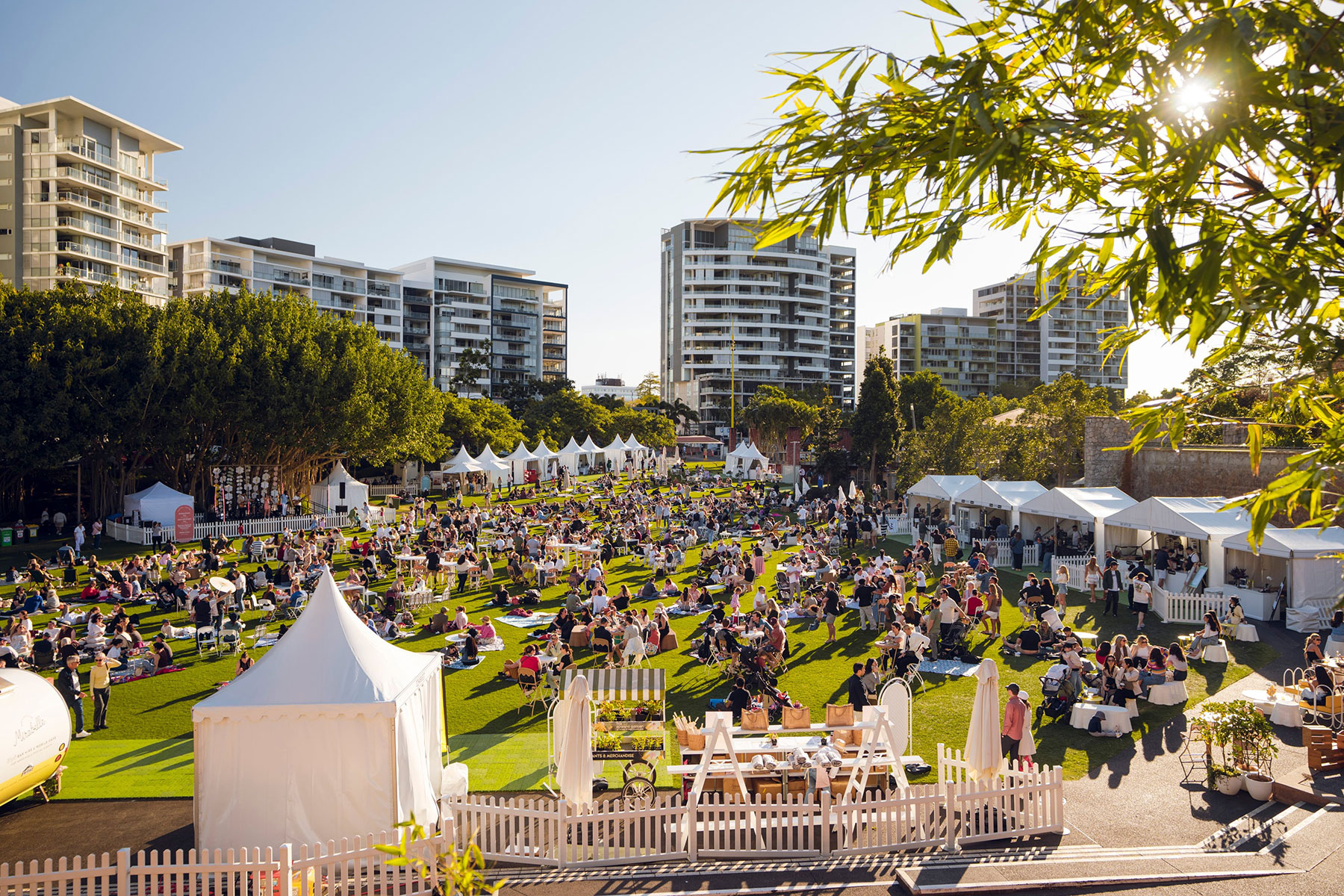 Providore Park Event Sire populated with people white marquees and event furniture on a green lawn on a sunny day