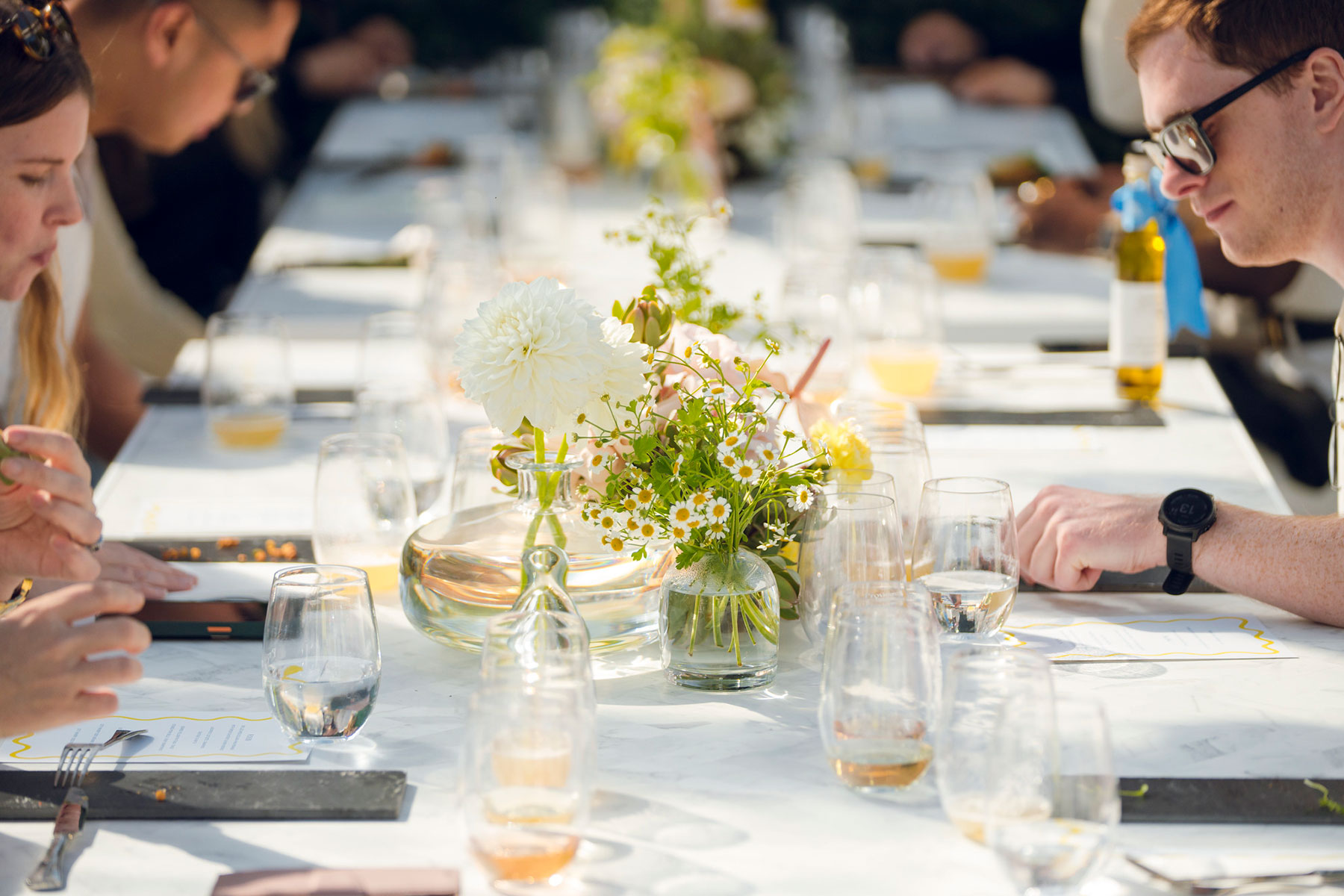 Table set with white table cloth with flowers and cultlery and glass table settings