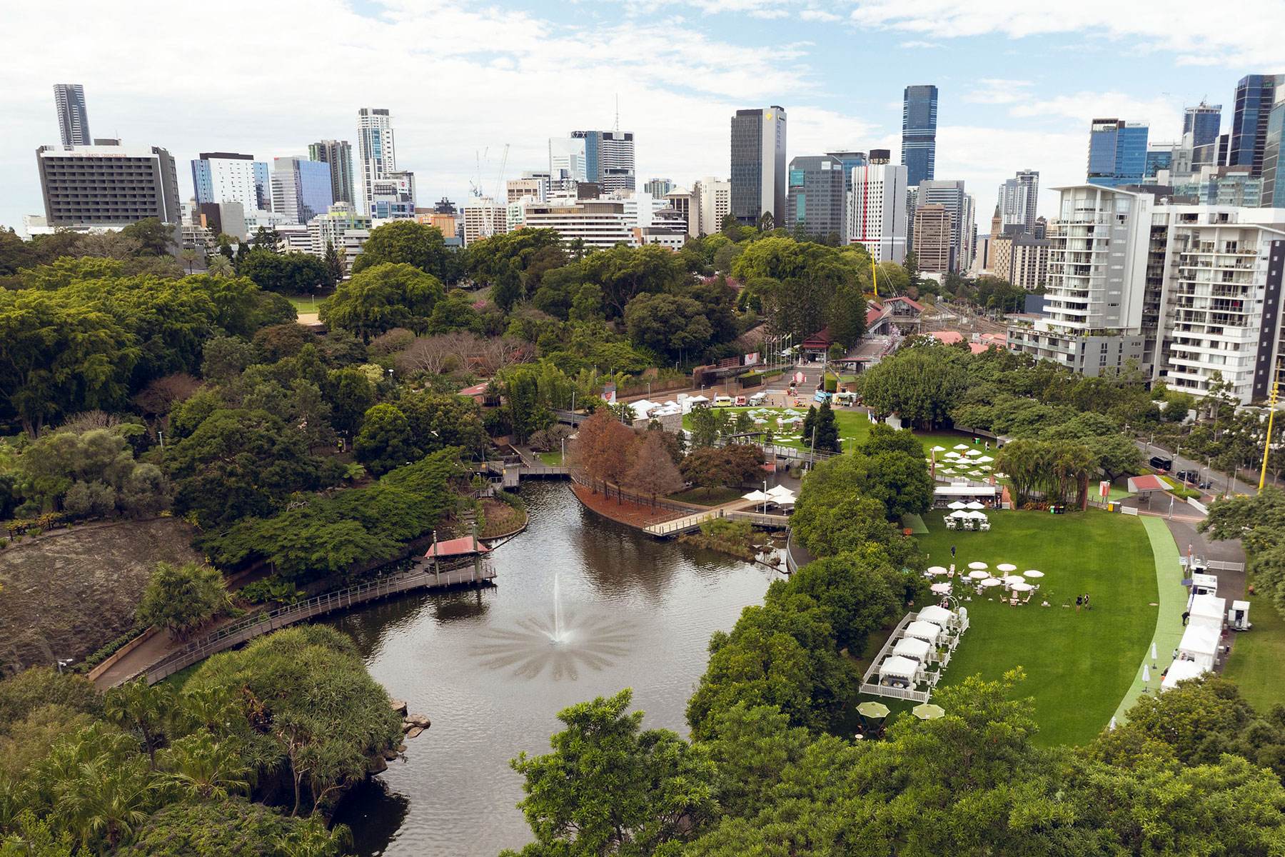 Aerial shot of Roma Street Parkland featuring the lake with a fountain and white marquees set on the lawns