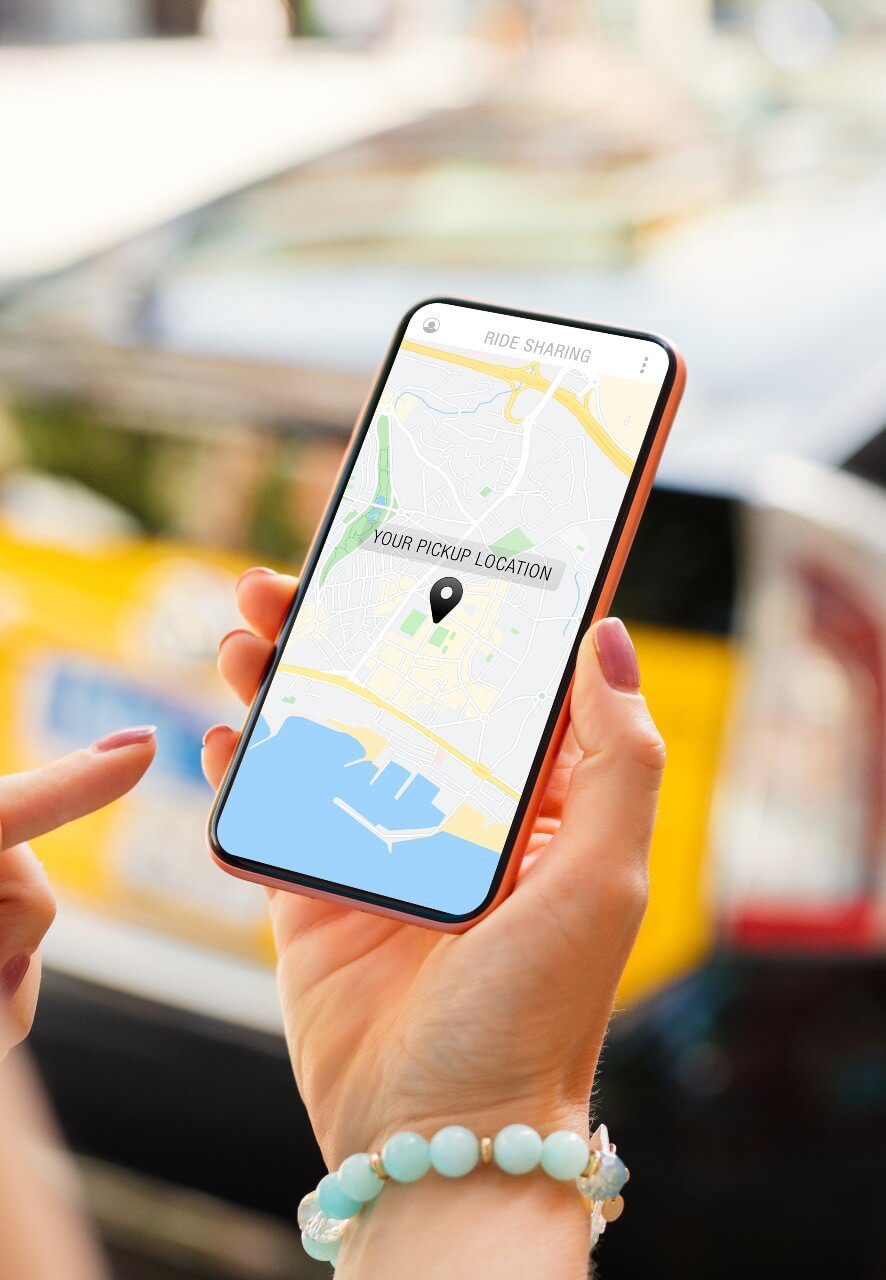 Close-up of a person using a rideshare app on a smartphone, showing a map with a pickup location pinned.